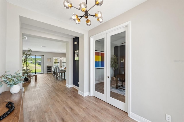 entryway with baseboards, an inviting chandelier, french doors, and light wood-style flooring