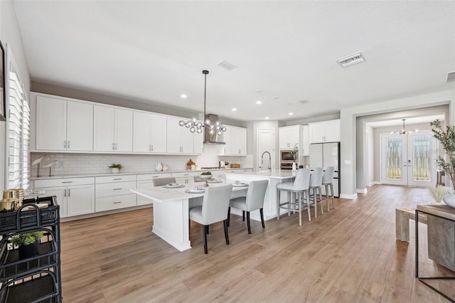 kitchen featuring backsplash, refrigerator, a notable chandelier, and visible vents