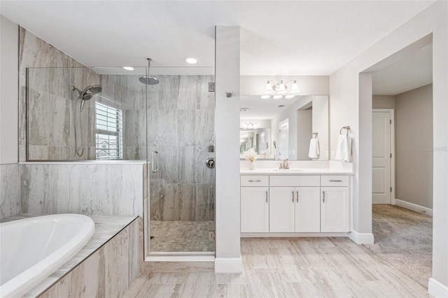 bathroom featuring vanity, a bath, baseboards, and a stall shower