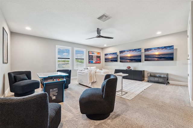 living area featuring carpet floors, baseboards, a ceiling fan, and visible vents