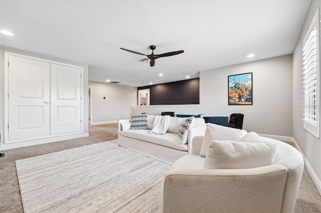 living room featuring ceiling fan, light colored carpet, and baseboards