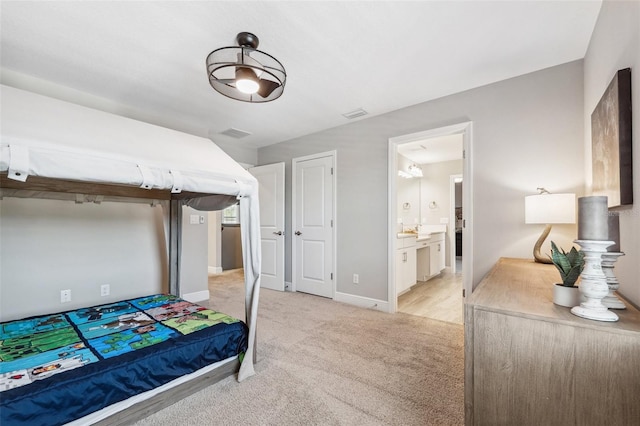 bedroom featuring baseboards, ensuite bathroom, light carpet, and visible vents