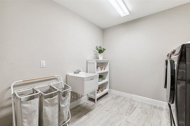 laundry area featuring baseboards, laundry area, wood finished floors, and washer and clothes dryer