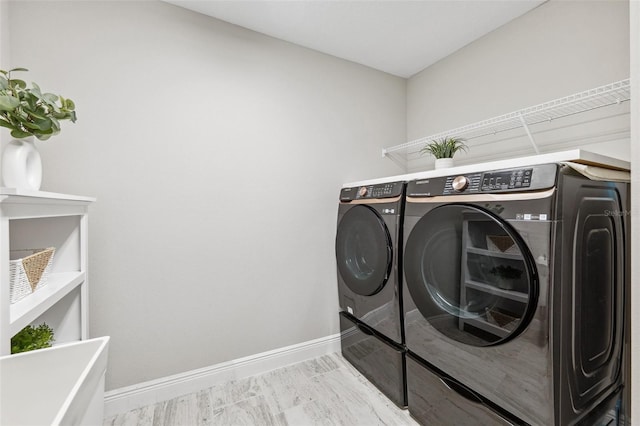 clothes washing area with laundry area, baseboards, and washer and dryer
