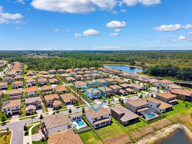 drone / aerial view with a water view, a residential view, and a forest view