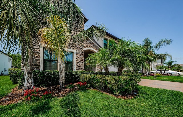 2653 Longleaf Pine Pt, New Port Richey, FL 34655 - view of property hidden behind natural elements featuring stone siding, a front lawn, and decorative driveway