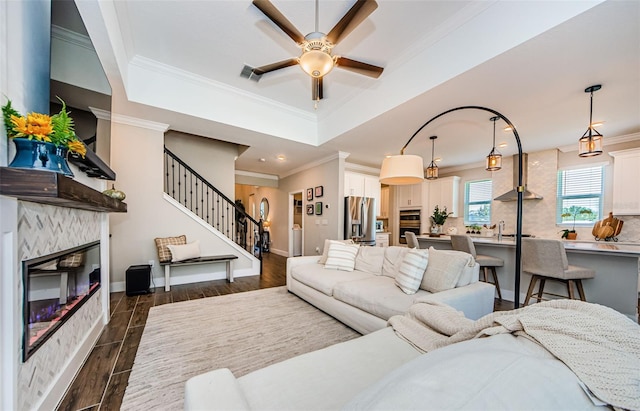 2653 Longleaf Pine Pt, New Port Richey, FL 34655 - living room with a ceiling fan, crown molding, a glass covered fireplace, dark wood-style flooring, and a tray ceiling