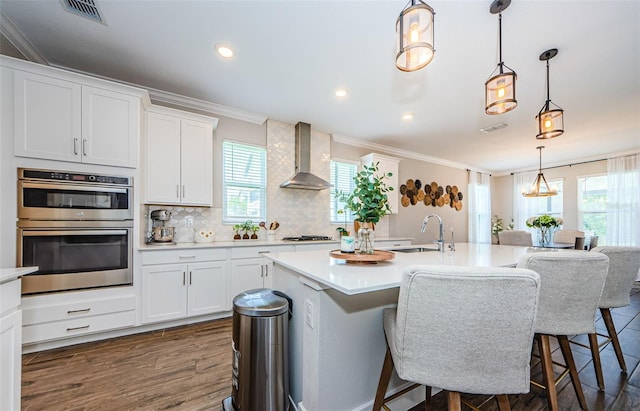 2653 Longleaf Pine Pt, New Port Richey, FL 34655 - kitchen with wall chimney exhaust hood, stainless steel appliances, ornamental molding, plenty of natural light, and light countertops
