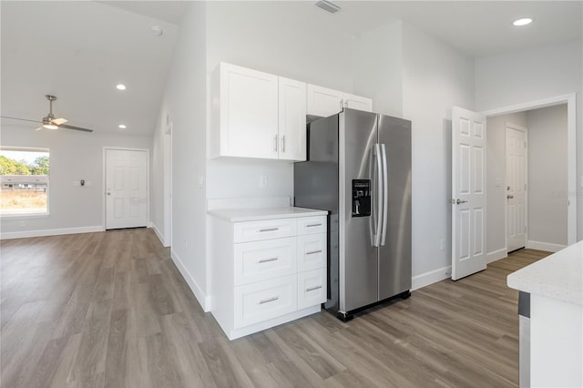 kitchen featuring a ceiling fan, stainless steel refrigerator with ice dispenser, light countertops, white cabinets, and light wood finished floors