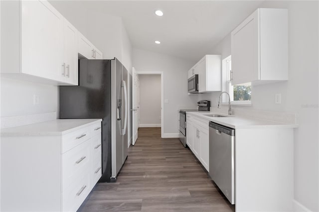 kitchen featuring white cabinets, appliances with stainless steel finishes, a sink, recessed lighting, and vaulted ceiling