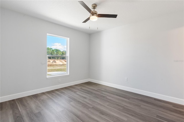 unfurnished room featuring baseboards, dark wood finished floors, and ceiling fan