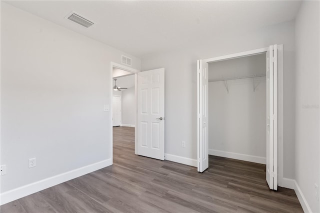 unfurnished bedroom with baseboards, a closet, wood finished floors, and visible vents