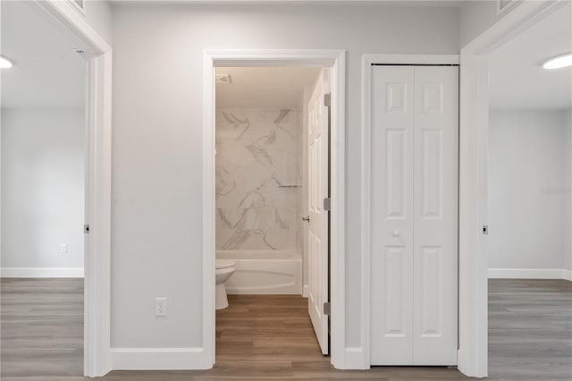 full bathroom with a closet, baseboards, wood finished floors, and toilet
