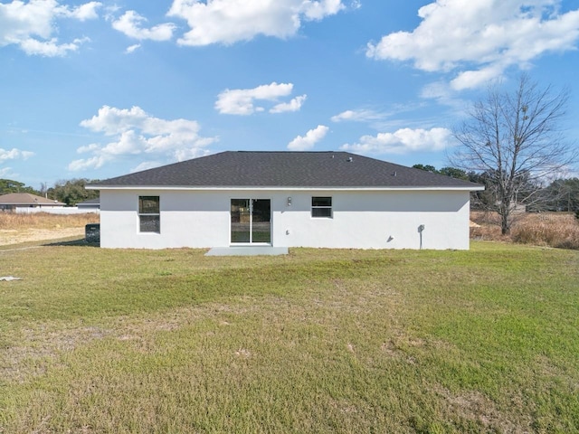 rear view of house with a lawn and stucco siding