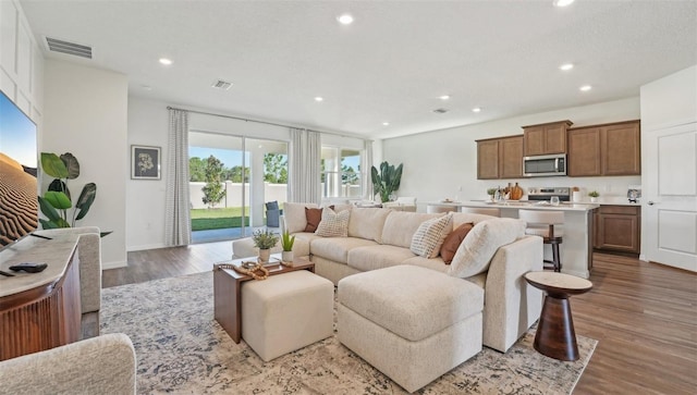 living room featuring baseboards, recessed lighting, wood finished floors, and visible vents