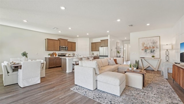 living room with recessed lighting, visible vents, and wood finished floors