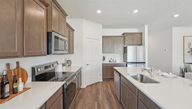 kitchen with light countertops, a sink, dark wood-style flooring, and stainless steel appliances