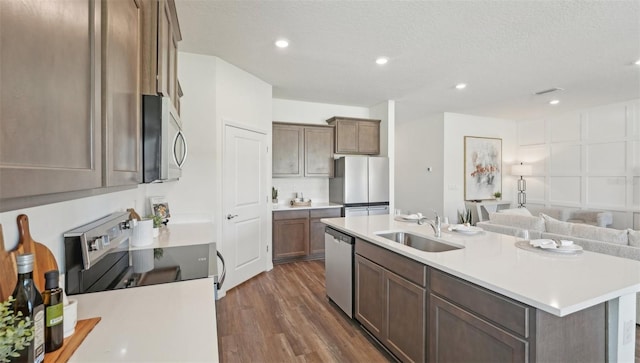 kitchen featuring light countertops, stainless steel appliances, a sink, and dark wood-type flooring