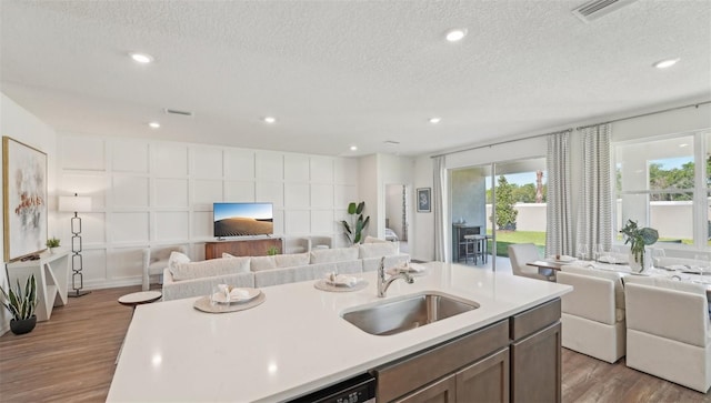 kitchen with light countertops, open floor plan, a sink, and light wood finished floors