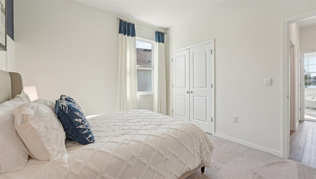 carpeted bedroom featuring baseboards, multiple windows, and a closet
