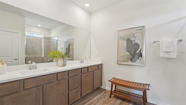full bath featuring wood finished floors, a sink, a stall shower, and double vanity