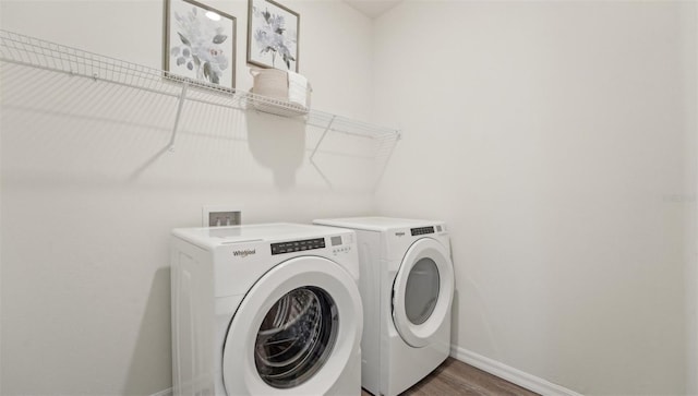 clothes washing area featuring independent washer and dryer, laundry area, baseboards, and wood finished floors