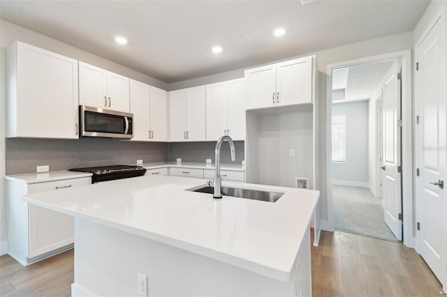 4717 W Mccoy St Unit 2, Tampa, FL 33616 - kitchen with stainless steel microwave, a sink, light wood-type flooring, white cabinetry, and recessed lighting