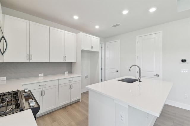 4717 W Mccoy St Unit 2, Tampa, FL 33616 - kitchen featuring a sink, light wood-type flooring, white cabinets, recessed lighting, and light countertops