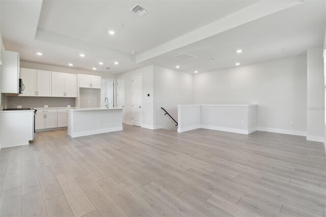 4717 W Mccoy St Unit 2, Tampa, FL 33616 - unfurnished living room with light wood finished floors, recessed lighting, a raised ceiling, and baseboards