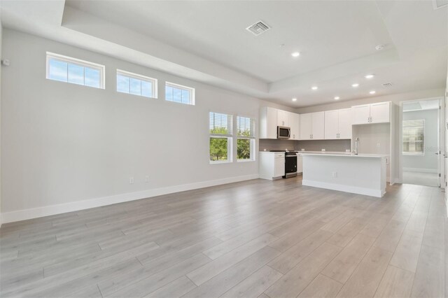 4717 W Mccoy St Unit 2, Tampa, FL 33616 - unfurnished living room with a raised ceiling, recessed lighting, light wood-type flooring, baseboards, and a sink