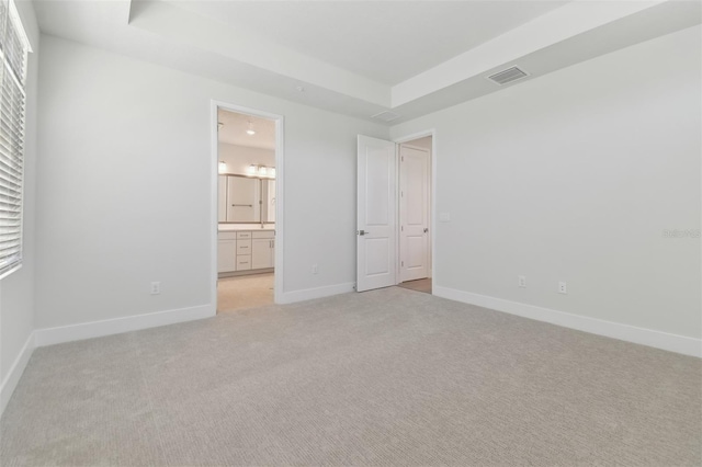 4717 W Mccoy St Unit 2, Tampa, FL 33616 - unfurnished bedroom featuring light colored carpet, a raised ceiling, baseboards, and connected bathroom