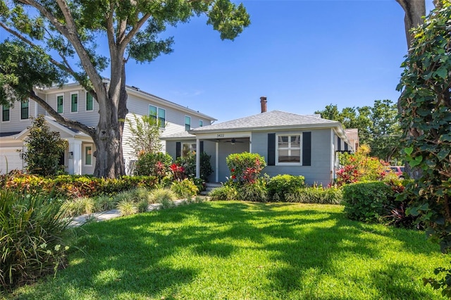 view of front of house featuring a shingled roof and a front yard