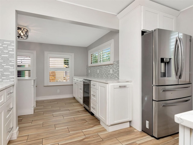 kitchen with stainless steel fridge, decorative backsplash, white cabinets, and wine cooler