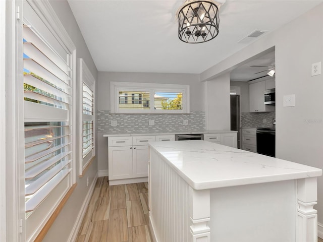kitchen with decorative backsplash, stainless steel microwave, range with electric stovetop, and visible vents