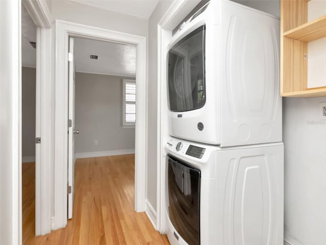 laundry room featuring laundry area, stacked washer and dryer, visible vents, light wood-type flooring, and baseboards