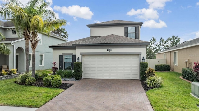 view of front facade with an attached garage, decorative driveway, a front lawn, and stucco siding