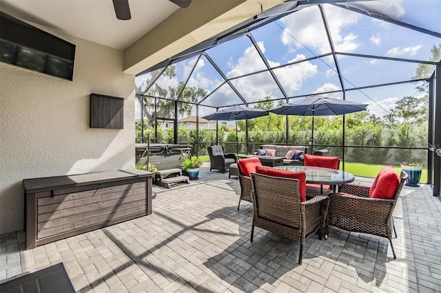 view of patio featuring outdoor dining space, a hot tub, ceiling fan, outdoor lounge area, and glass enclosure