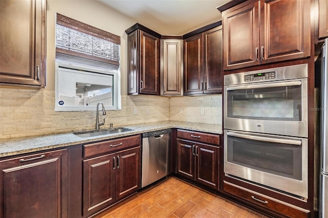 kitchen with light stone counters, a sink, backsplash, and stainless steel appliances