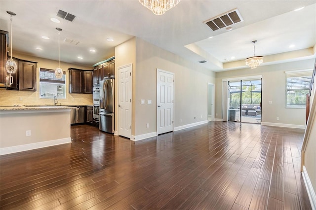 unfurnished living room featuring a chandelier, visible vents, and dark wood finished floors