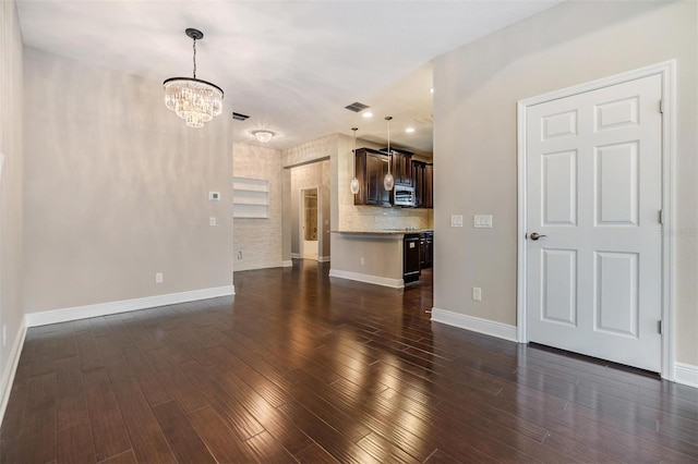 unfurnished living room with a notable chandelier, recessed lighting, baseboards, dark wood-type flooring, and visible vents