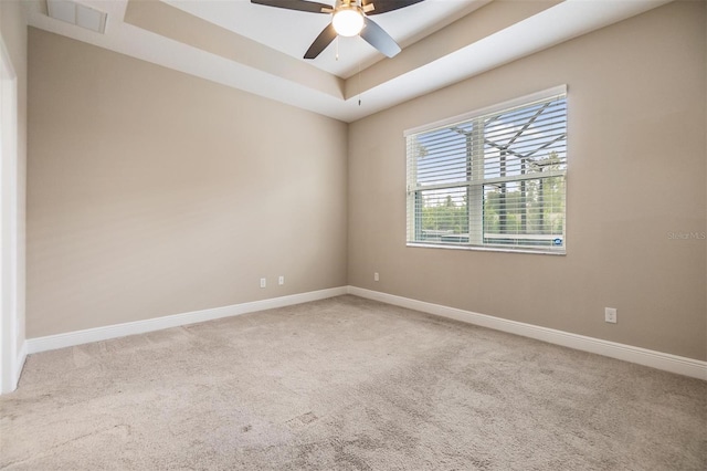 carpeted spare room with baseboards, ceiling fan, and a raised ceiling