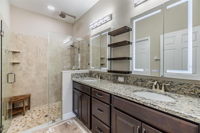 full bath featuring double vanity, a sink, and a stall shower