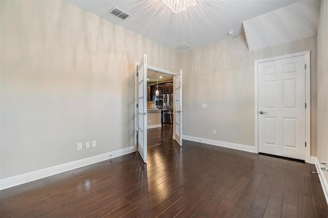 spare room with visible vents, baseboards, and dark wood-style floors