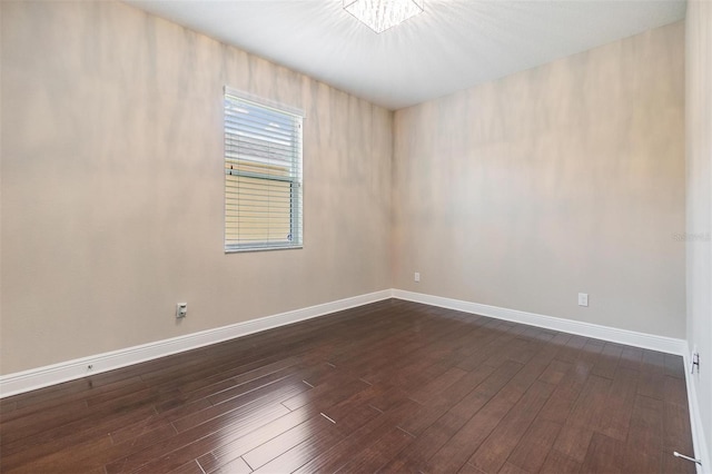 spare room featuring baseboards and dark wood-style flooring