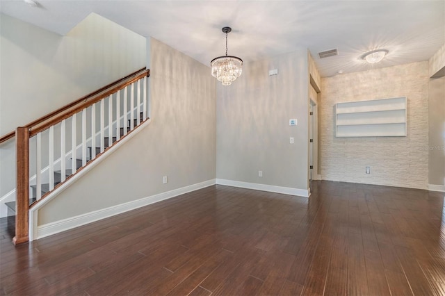 unfurnished living room featuring visible vents, wood finished floors, baseboards, a notable chandelier, and stairs