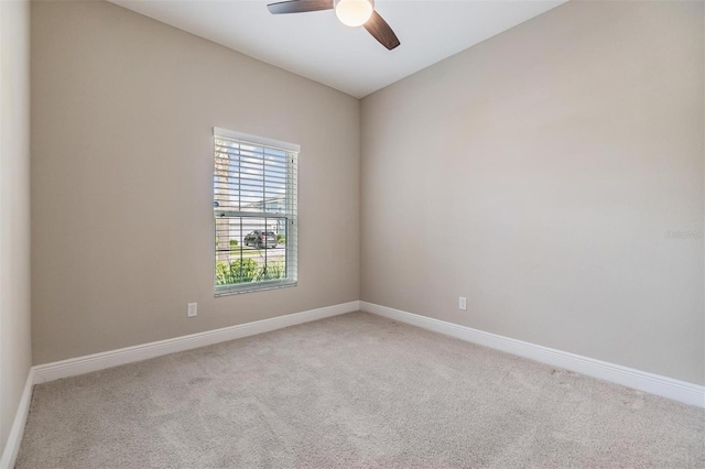 carpeted empty room featuring baseboards and a ceiling fan