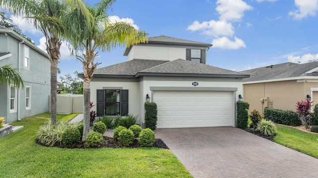 view of front of property featuring a shingled roof, an attached garage, a front lawn, stucco siding, and decorative driveway