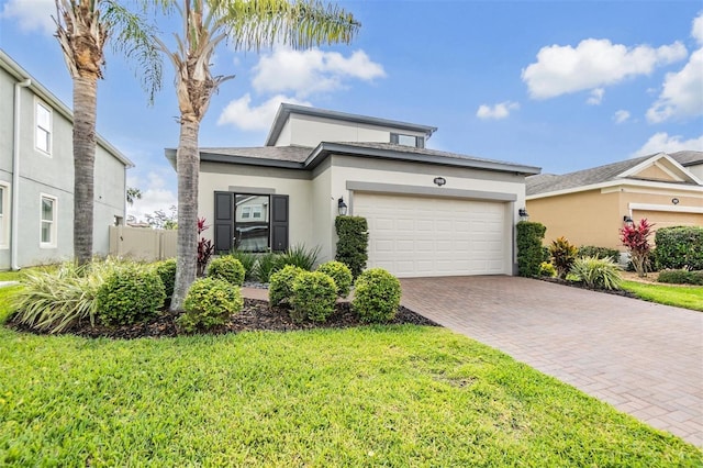view of front of home featuring a garage, stucco siding, a front lawn, and decorative driveway