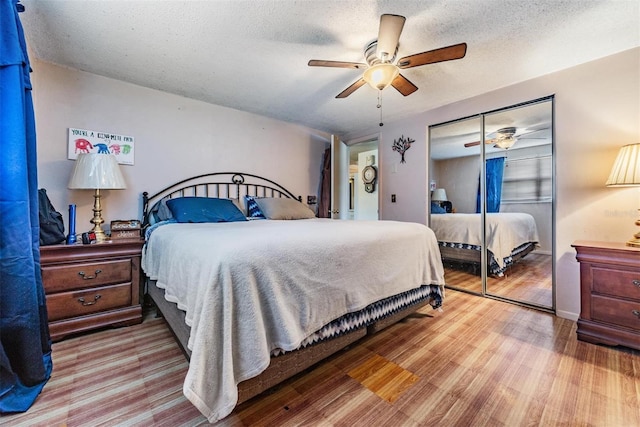bedroom with a textured ceiling, ceiling fan, wood finished floors, and a closet