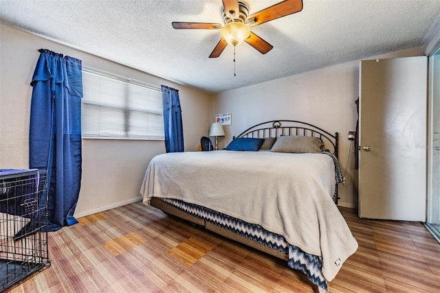 bedroom featuring baseboards, a ceiling fan, a textured ceiling, and wood finished floors